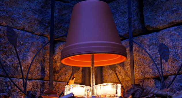 Teelichtofen: Zwei Tontöpfe auf einer Stange hängen wie ein Lampenschirm über drei Teelichtern. Foto: TwilightArtPictures / stock.adobe.com