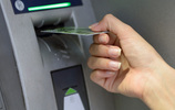 Eine Hand führt eine Plastikkarte in den Schlitz eines Geldautomaten ein. Bild: Khorzhevska / Fotolia.com