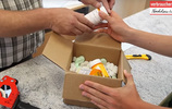 Hände nehmen eine Pillendose aus einem Paket. Foto: Zollarchiv/Verbraucherzentrale NRW